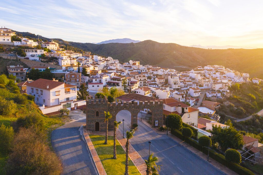 Vista aérea al amanecer del arco de entrada a Moclinejo y el pueblo de fondo