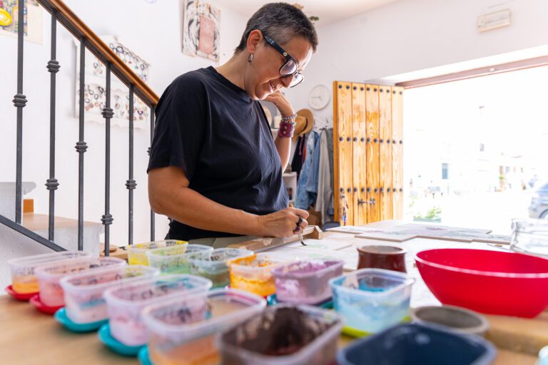 Una mujer pintando un objeto en una mesa en un taller de artesanía en Moclinejo