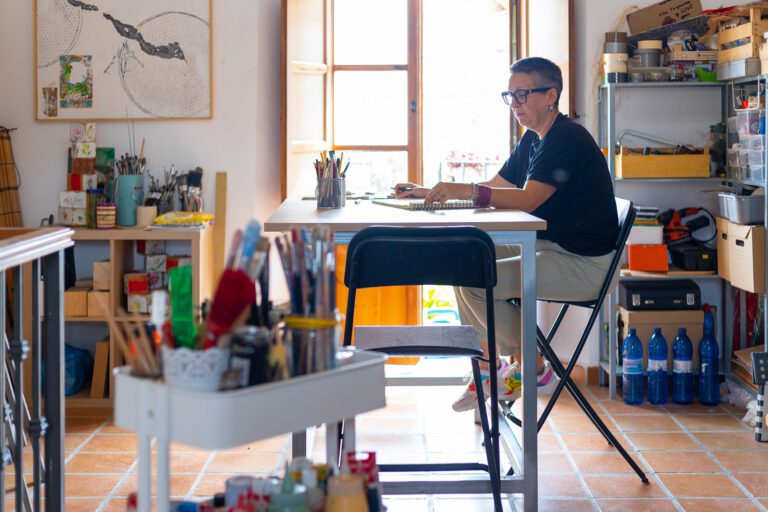 Una mujer pintando un objeto en una mesa en un taller de artesanía en Moclinejo