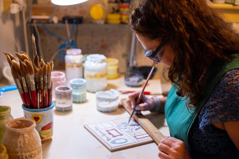 Una mujer pintando un objeto en una mesa en un taller de artesanía en Moclinejo