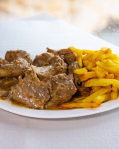 Plato de chivo de la Axarquía en salsa de almendras con guarnición de patatas fritas