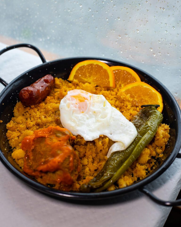 Sartén de migas malagueñas con lomo en manteca, huevo frito, chorizo, pimiento y naranja