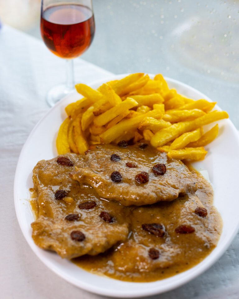 Plato de solomillo a la pasa moscatel con guarnición de patatas fritas una copa de vino moscatel
