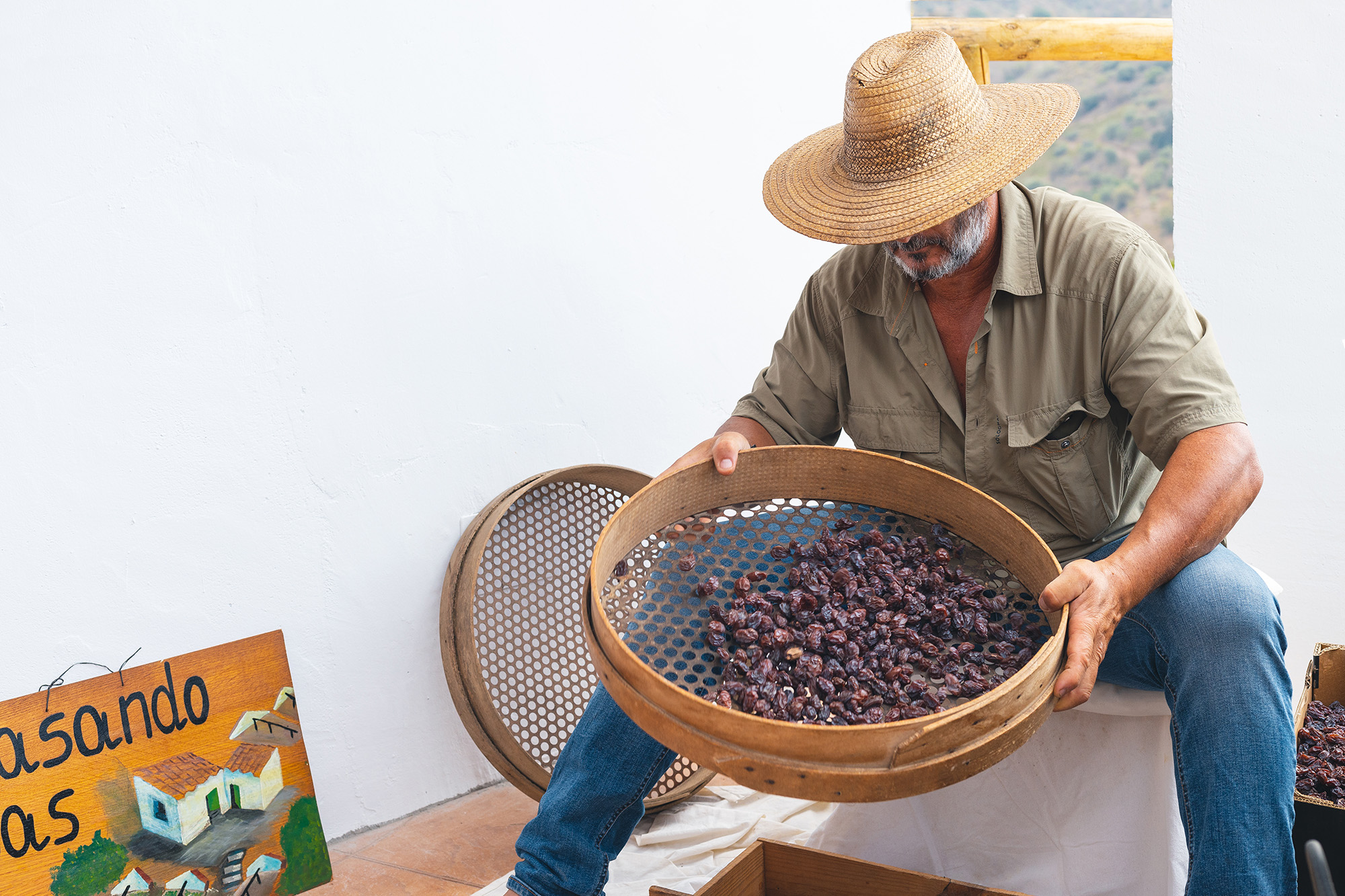 Un hombre con un sombrero sentado cribando pasas