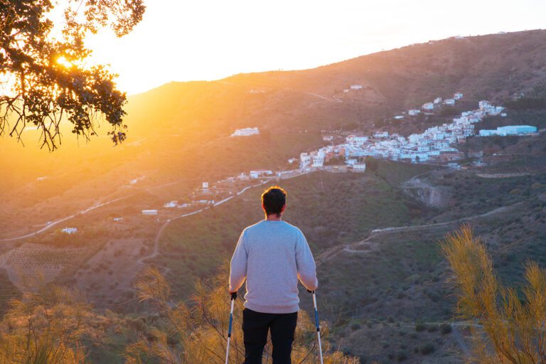 Hombre senderista mirando hacia Moclinejo desde una ruta de senderismo al atardecer